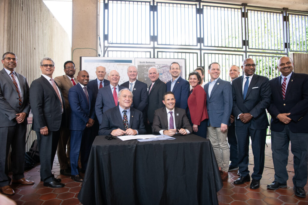 County executives gathered together. Two males seated in front, smiling.