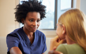 African American female nurse treating a young girl.