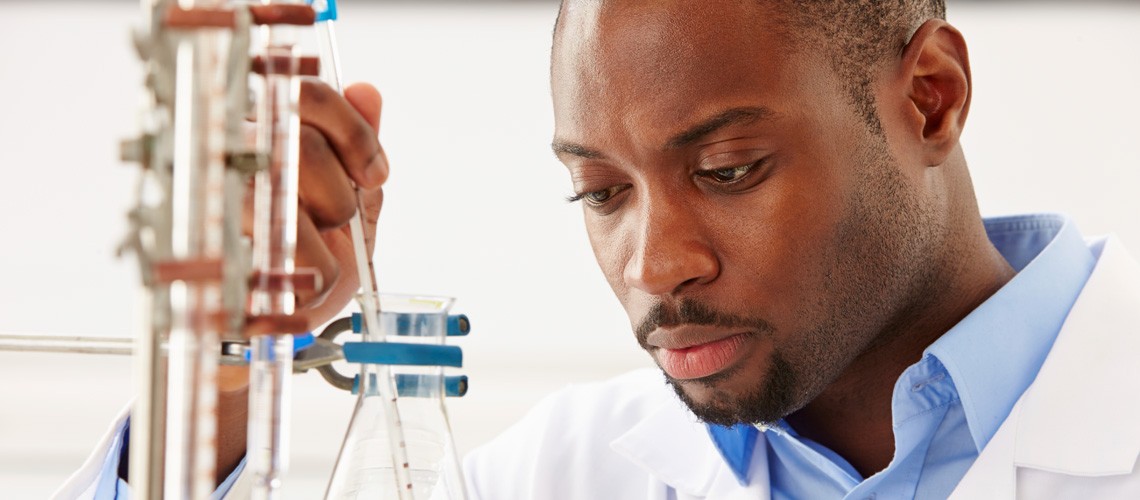 African American male in a lab with a beaker.